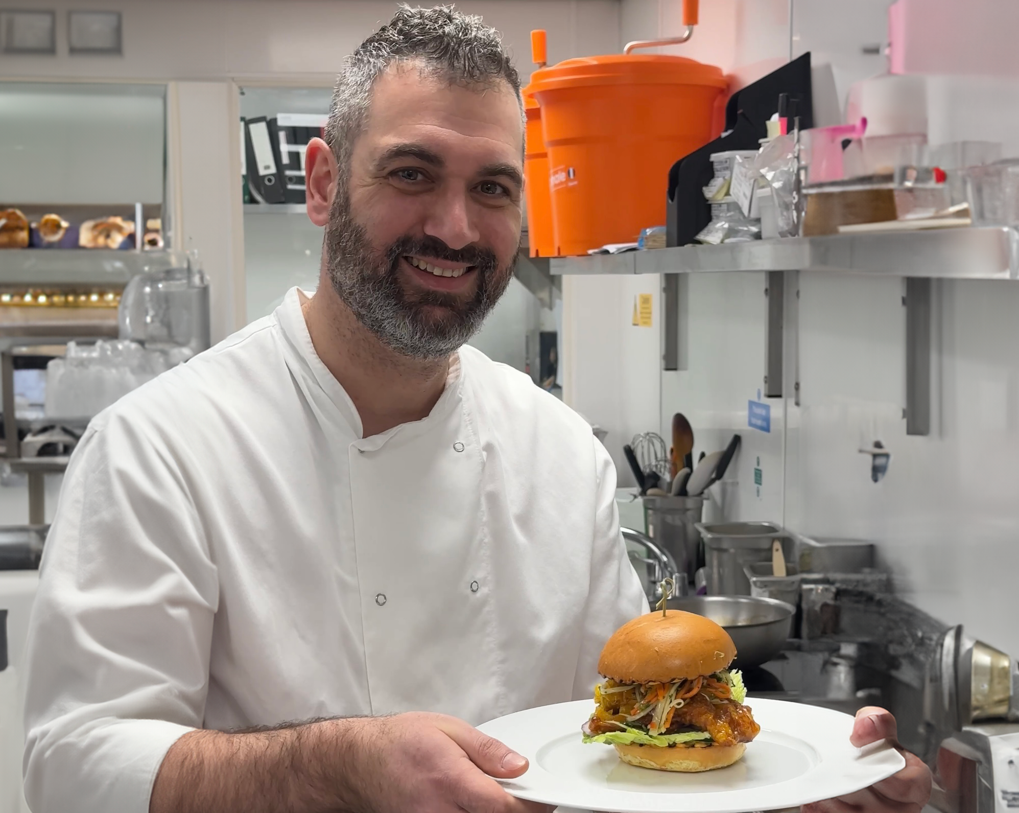 chef holding a vegan burger on a plate